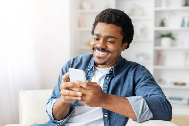 istock Man Sitting on Couch Looking at Cell Phone 2156332522