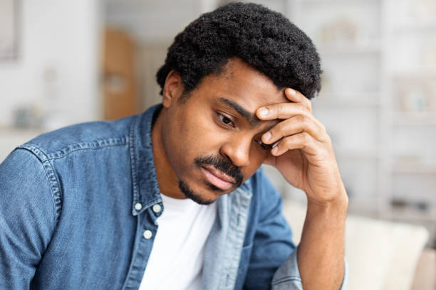 istock Upset Man Sitting on a Couch With Hand on Head 2156332526