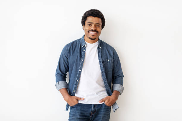 istock Black Man Standing Confidently With Hands In Pockets Against White Wall Background 2156332562