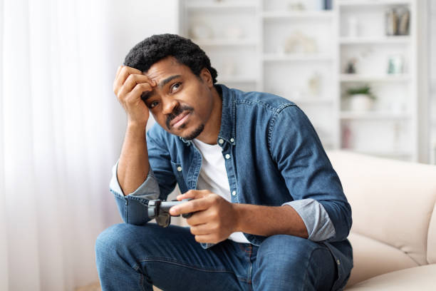 istock Concerned Young Black Man Holding Joystick And Touching Head 2156332692