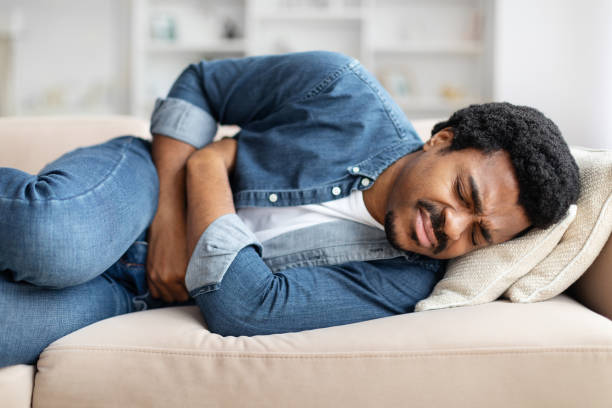 istock Black Man Experiencing Stomach Pain While Lying on Couch At Home 2156332731