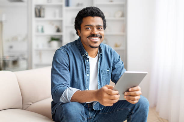istock Smiling man holding a tablet at home 2156332769