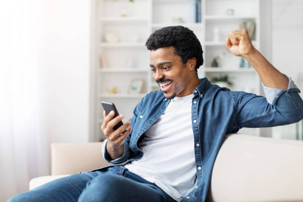 istock Man Sitting on Couch Holding Cell Phone, Gesturing 2156332809