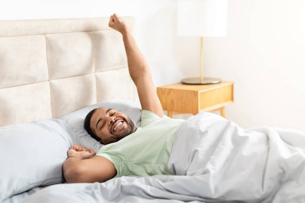 istock Happy african american guy lying in bed and stretching 2156334374