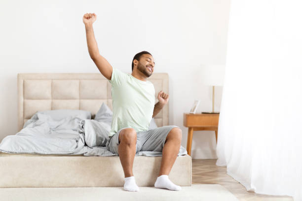 istock Happy well-rested black man stretching in bed 2156334410