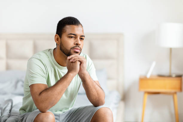 istock Pensive black man sitting on bed looking away 2156334424