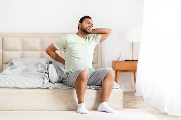 istock Man stretching back in bedroom morning 2156334427