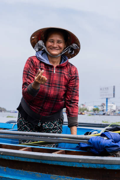 Hội An-Vietnam/17-March/2024:  Fisherman transported fish catch across  South China Sea.   Fisherman is wearing a conical head.\nIn the background are two fishing boats.
