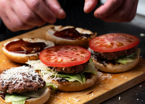 istock Chef placing tomatoes on burgers 2156339642