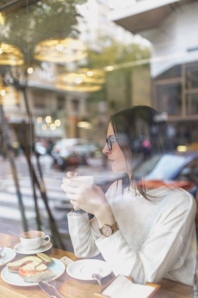 istock Young woman drinking hot beverage in cafe 2156340325