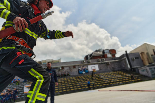 A senior Caucasian woman works as a firefighter dressed in a uniform.The adult woman leans out of the balcony to see the extent of the fire.Concept of women in risky professions.