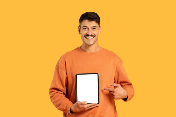 istock Man holding tablet with blank screen on yellow background 2156349763