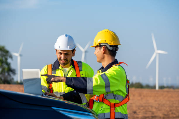 istock Diverse ethnicity male technicians working in the wind turbines field. Innovation engineer men use laptop computer work to develop environmental renewable clean energy outdoors at windmill power farm. 2156350517