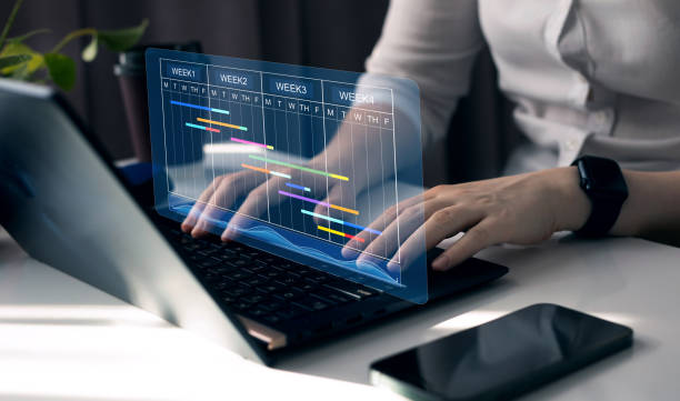 istock Project manager working on laptop and updating tasks and milestones progress planning with Gantt chart scheduling interface for company on virtual screen. Business Project Management System. 2156351256