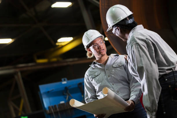 istock Two multiracial women engineers in warehouse with plans 2156353832