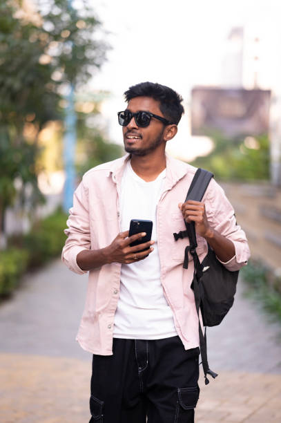istock Young Man Walking Outdoors with Backpack and Smartphone 2156357507