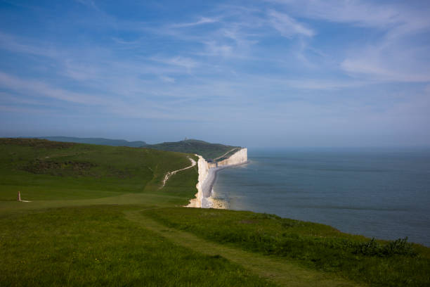 A wide view of the Seven Sisters and Birling Gap, with the Tout Belle Lighthouse on the horizon on a sunny day in East Sussex.