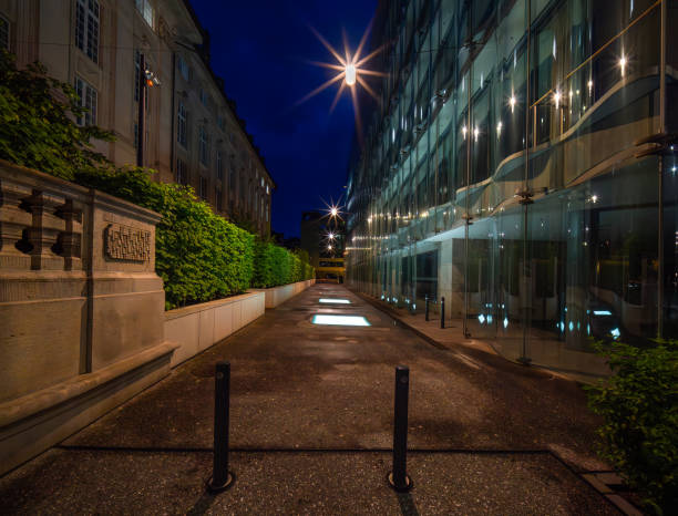 Lit urban alleyway in Zurich, Switzerland, at night with modern and classical buildings, green bushes, light stars