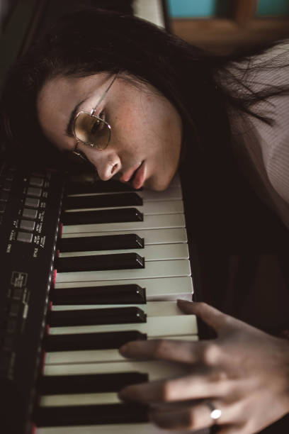 istock young woman with her head resting on the piano 2156369322