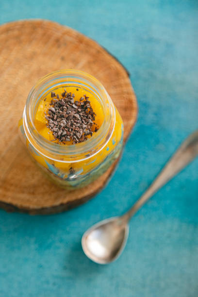 top view of mango tropical dessert with chia cacao nibs topping and silver spoon over blue background