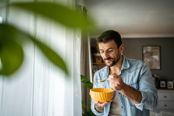 istock Happy young man eating cornflakes for breakfast at home 2156375402