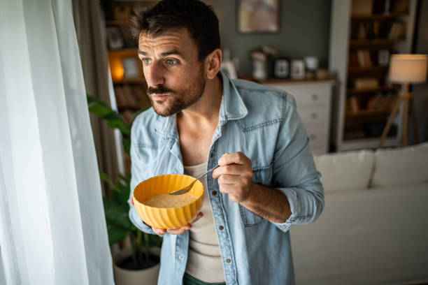 istock Happy young man eating cornflakes for breakfast at home 2156375438