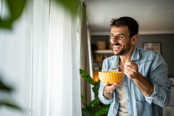 istock Happy young man eating cornflakes for breakfast at home 2156375480