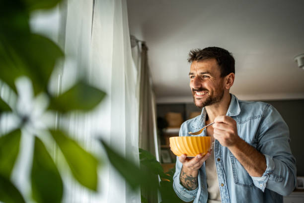 istock Happy young man eating cornflakes for breakfast at home 2156375511