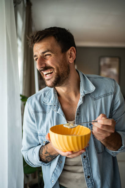 istock Happy young man eating cornflakes for breakfast at home 2156375521