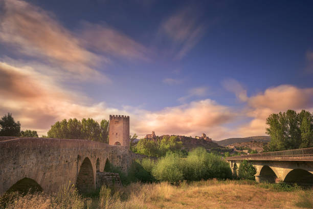 View of the medieval bridge of Frias, in Burgos and in the background the town of Frias, highlighting its church and castle against the sky at dawn
