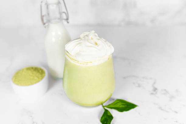 istock Matcha green tea in a glass with whipped cream on a light gray background. 2156379327