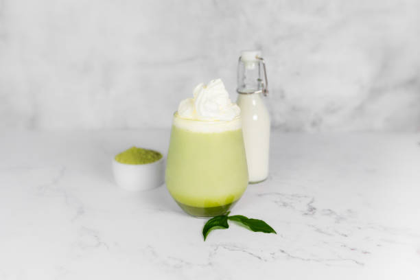 istock Matcha green tea in a glass with whipped cream on a light gray background. 2156379334