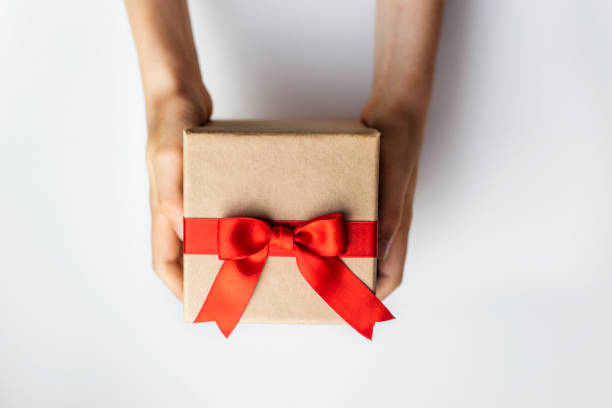 istock hands holding gift box with red ribbon isolated on white background 2156380631