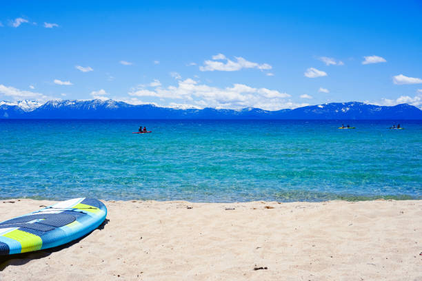 Paddle board on beach, people kayaking at the background