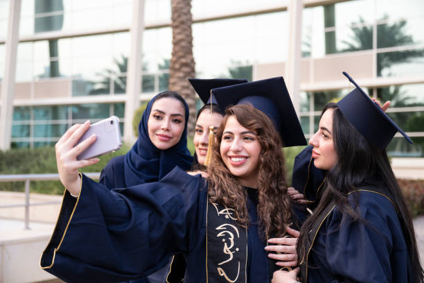 Female students taking selfie with their professor on graduation day