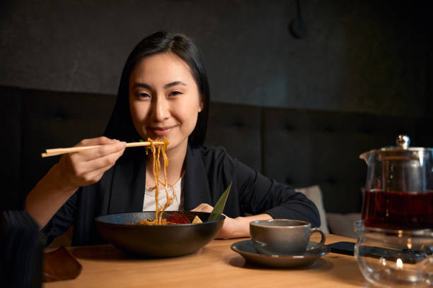 istock Asian woman eating delectable seafood ramen and drinking tea 2156382142