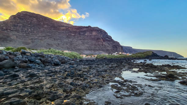 Panoramic view on massive sharp cliffs and mountains in village Valle Gran Rey, La Gomera, Canary Islands, Spain, Europe. Vista on beach Playa Charco del Conde with shoreline of volcanic black rocks