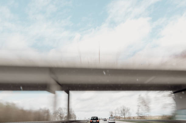 Cars drive at high speed on the highway through the rural landscape. Fast blurred highway driving. A scene of speeding on the highway.