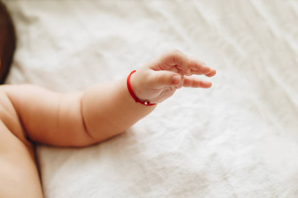 Baby's hands on white background of baby bedding. Concept of infancy, innocence, mother and baby, newborn, gentle, beginning.