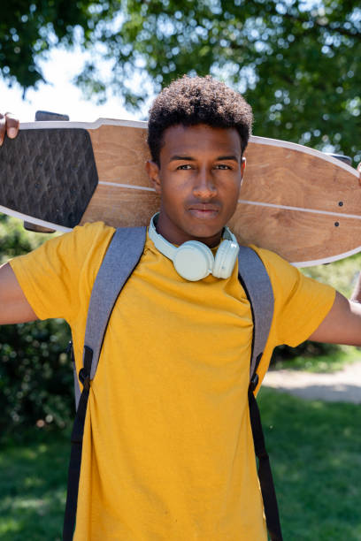 istock Young student posing with a longboard skateboard in a park 2156393359