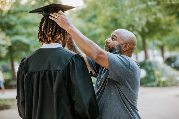 istock A dad helps his son adjust his mortarboard cap as he prepares for his graduation. 2156394101