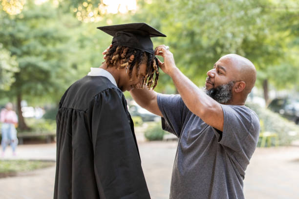 istock A father adjusts his son's mortarboard cap as he readies himself for graduation. 2156394105