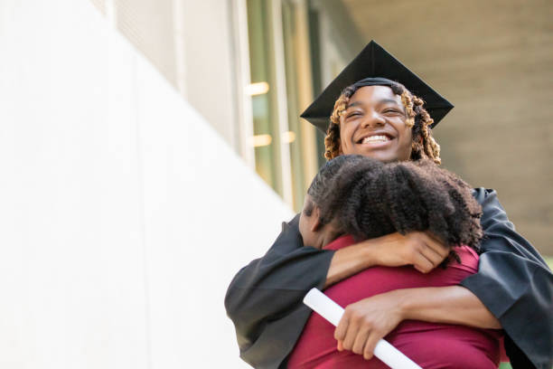 istock At a graduation celebration, a young black man and his sister share a hug. 2156394126