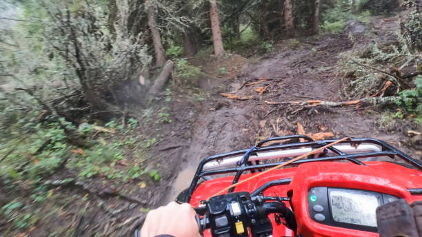POV of young man drives all terrain vehicle on muddy track