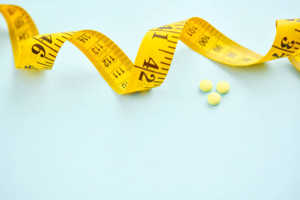 istock Tape measure with diet pills on a blue background 2156400242