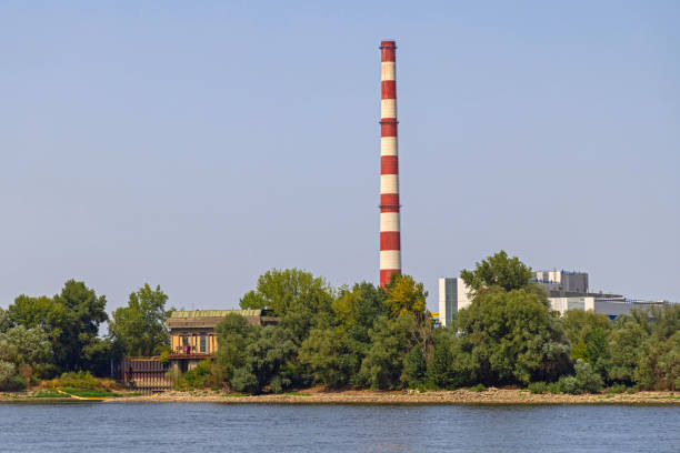 Novi Sad, Serbia - August 19, 2022: Tall Chimney Stack Thermal Power Plant Station at Danube River for City.