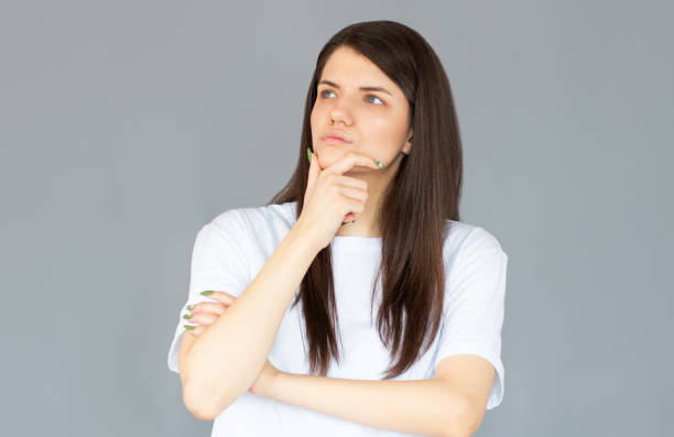 istock Thoughtful model in studio looking away. hand near the face. isolated gray background 2156406830