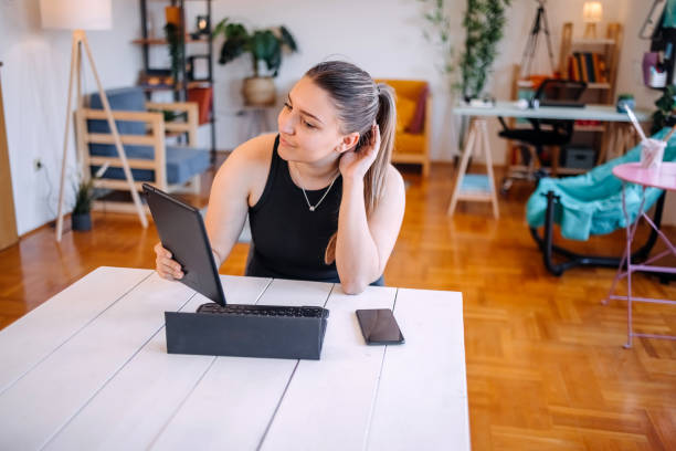 istock Young woman enjoying at home using digital tablet while sitting in kitchen 2156408021