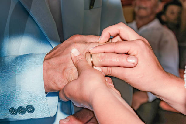 Close up unrecognizable bride putting wedding ring to her groom finger in the wedding ceremony