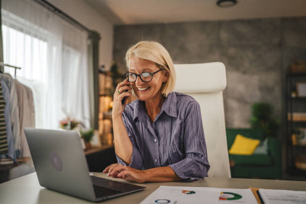 istock Mature woman work from home talk on mobile phone and hold document 2156408704